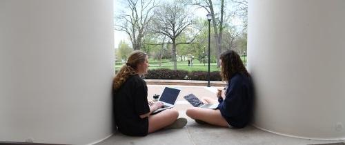 学生们拿着笔记本电脑坐在克伦斯大厅前